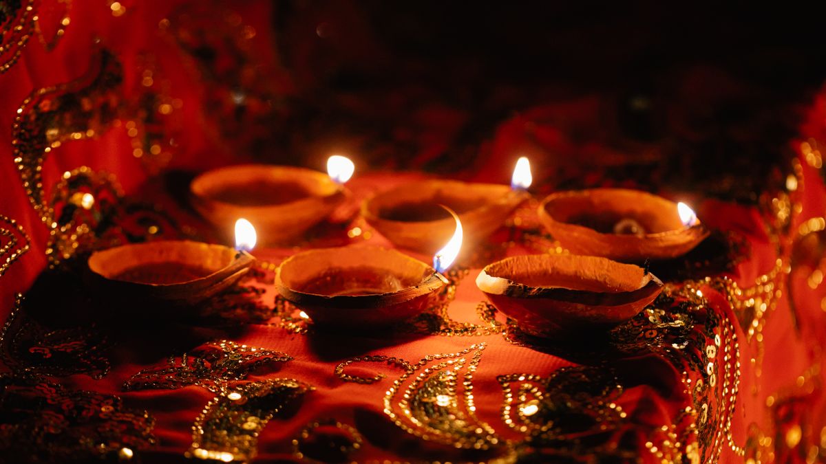 Traditional Indian oil lamps glowing on red and gold fabrics for an auspicious occasion